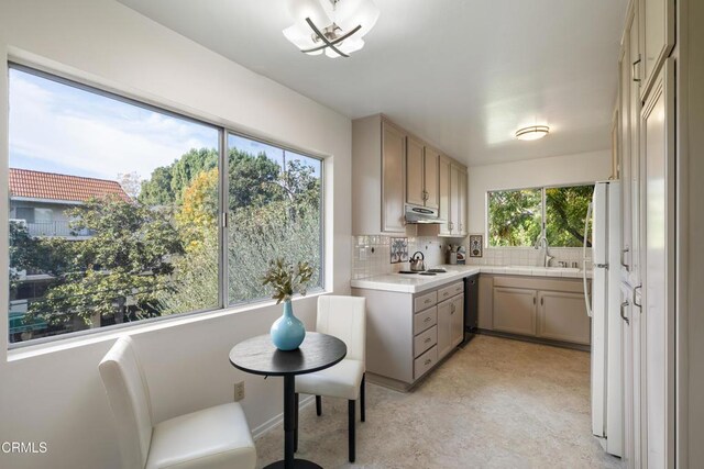 kitchen with light brown cabinetry, backsplash, sink, white refrigerator, and dishwasher