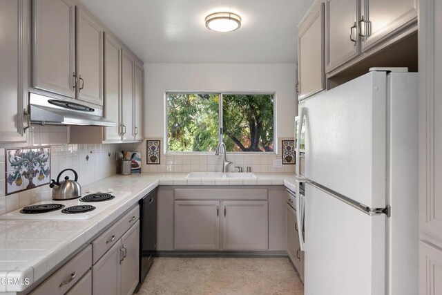 kitchen with tile countertops, white appliances, sink, decorative backsplash, and gray cabinets