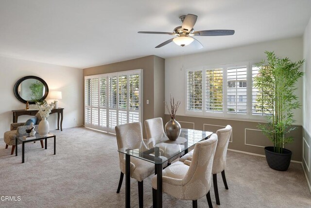 dining room with ceiling fan, a healthy amount of sunlight, and light carpet