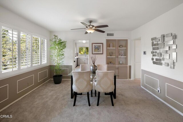 dining room with ceiling fan and light carpet