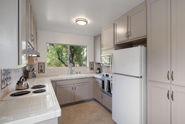 kitchen featuring backsplash, tile countertops, sink, and stainless steel appliances