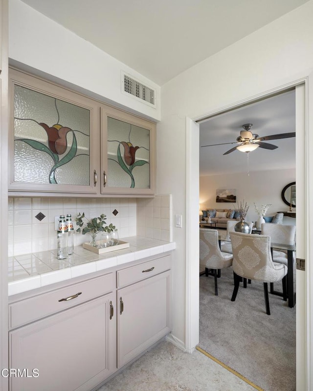 bar featuring light carpet, backsplash, tile counters, and ceiling fan