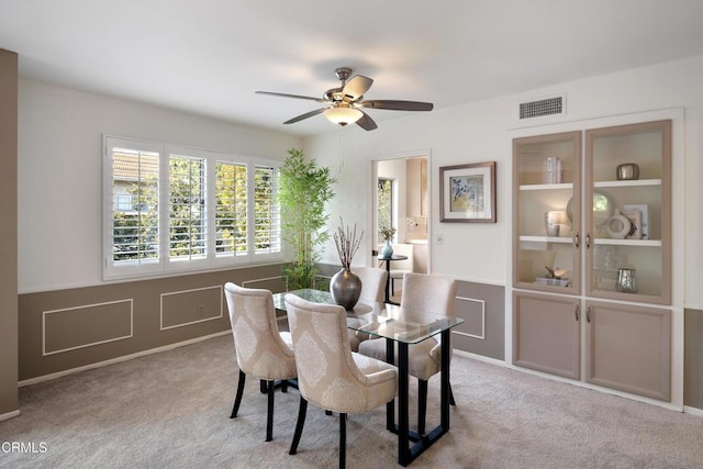 dining space with ceiling fan and light colored carpet