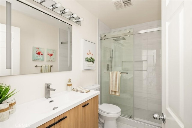 bathroom featuring tile patterned flooring, vanity, toilet, and a shower with shower door