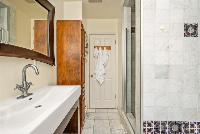 bathroom featuring a shower with door and sink