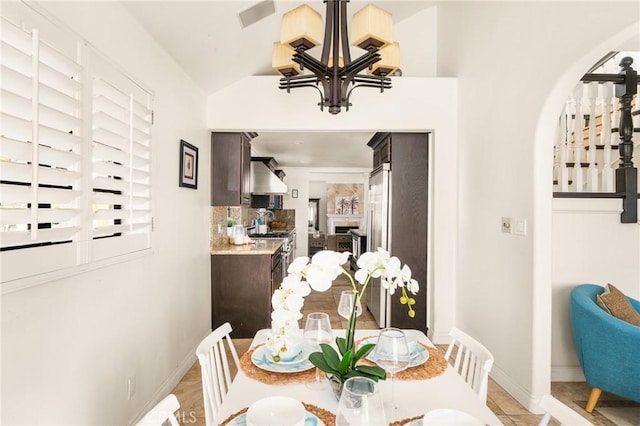 tiled dining space with vaulted ceiling and a notable chandelier