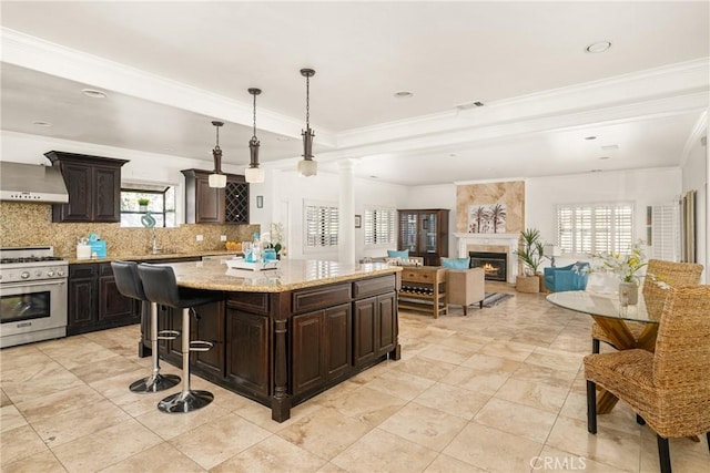 kitchen with a high end fireplace, dark brown cabinetry, a kitchen island, hanging light fixtures, and stainless steel range with gas stovetop