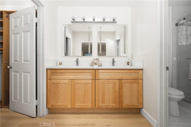 bathroom featuring hardwood / wood-style flooring, vanity, toilet, and a shower with shower door