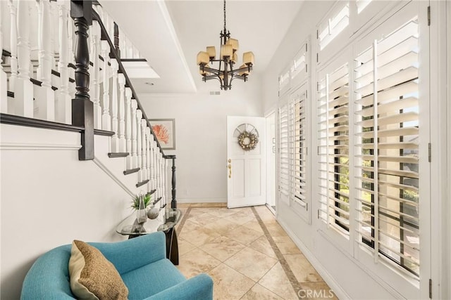 tiled entrance foyer featuring a healthy amount of sunlight, crown molding, and a chandelier