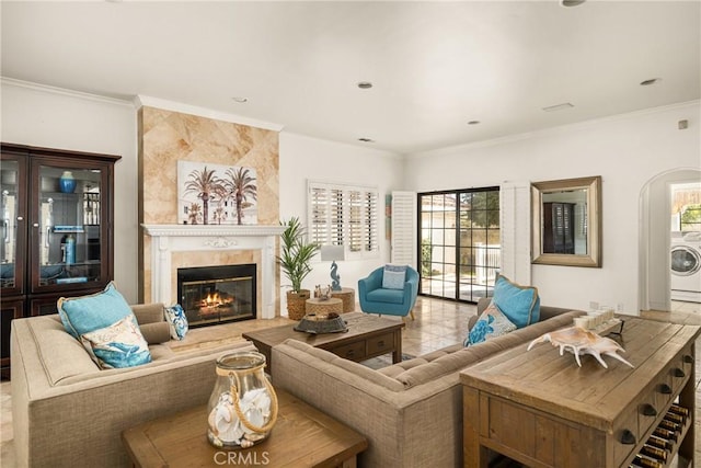 tiled living room with washer / clothes dryer, a premium fireplace, a healthy amount of sunlight, and ornamental molding