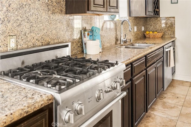 kitchen featuring tasteful backsplash, light stone counters, dark brown cabinets, stainless steel appliances, and sink