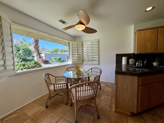 dining room featuring ceiling fan and sink