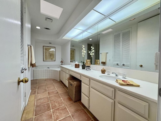 bathroom with tiled bath, tile patterned flooring, and vanity