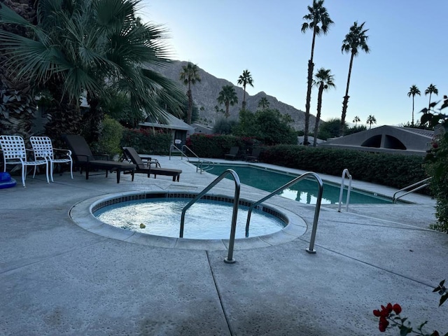 view of pool with a mountain view, a patio, and a hot tub