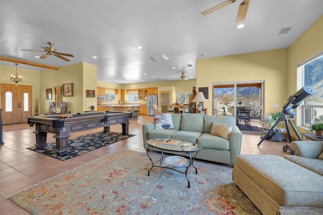 tiled living room with ceiling fan with notable chandelier, a healthy amount of sunlight, and billiards