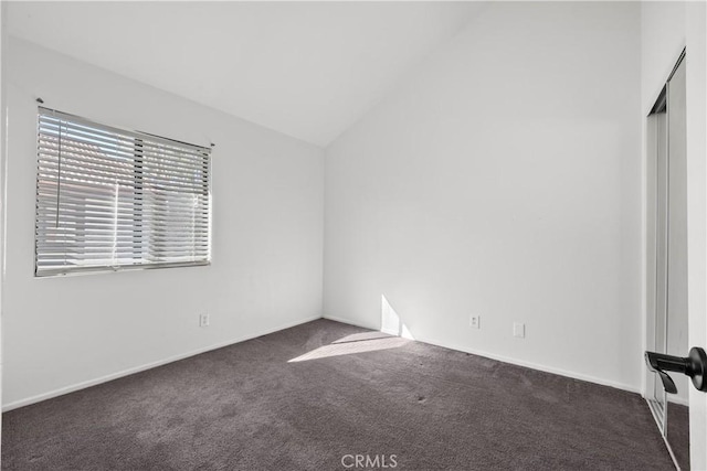 unfurnished room featuring dark carpet and lofted ceiling