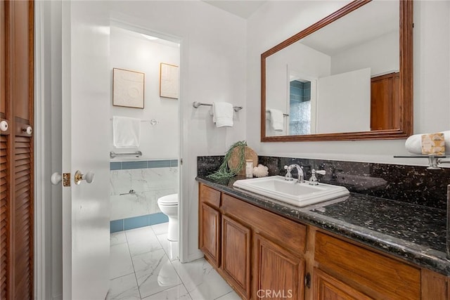 bathroom featuring vanity, tile walls, and toilet