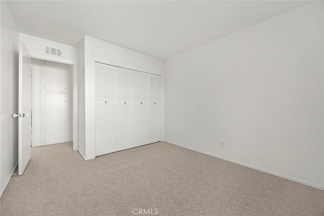 unfurnished bedroom with light colored carpet and a closet