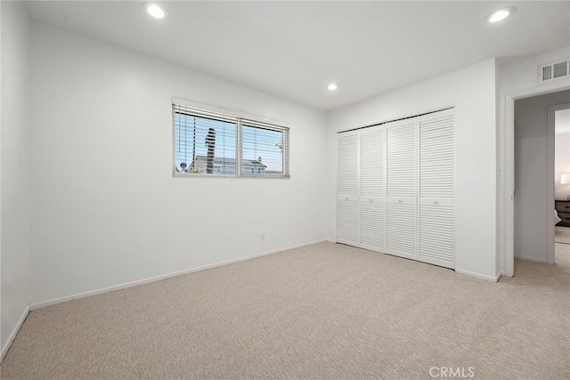 unfurnished bedroom featuring light carpet and a closet