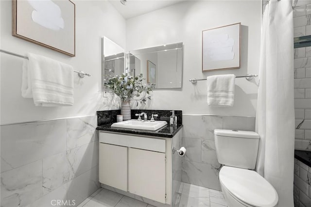 bathroom featuring vanity, toilet, and tile walls