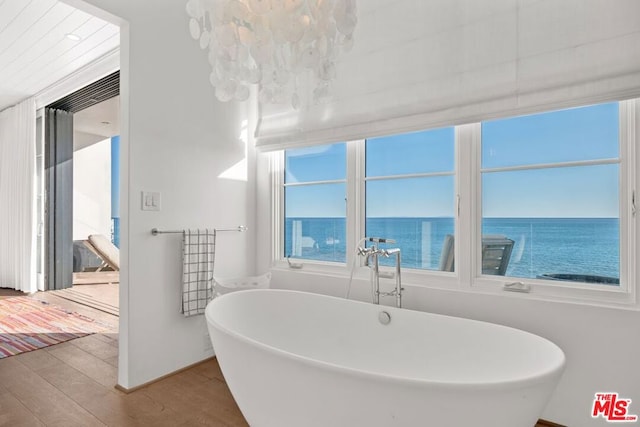 bathroom featuring a bathtub, a water view, and wood-type flooring