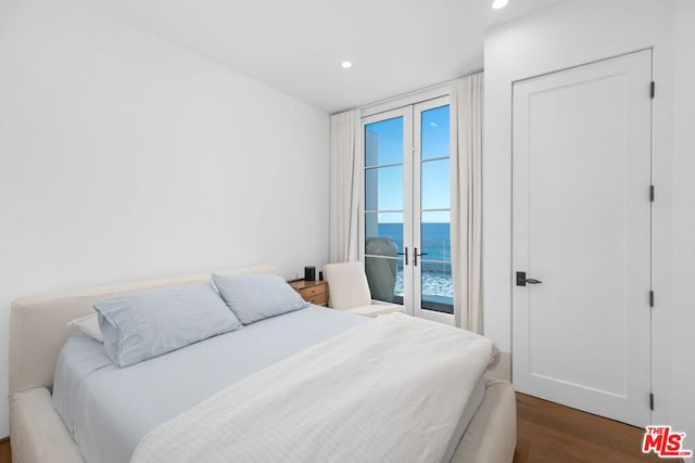 bedroom with access to outside, a water view, and dark hardwood / wood-style floors