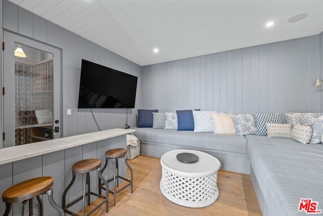 living room with light hardwood / wood-style floors and wooden walls