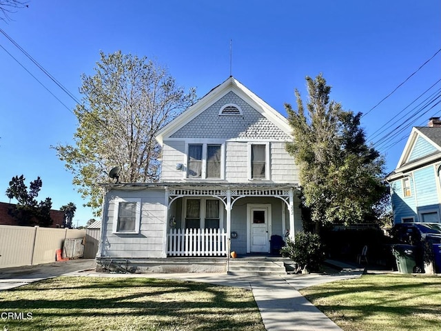 victorian house with a front yard and a porch