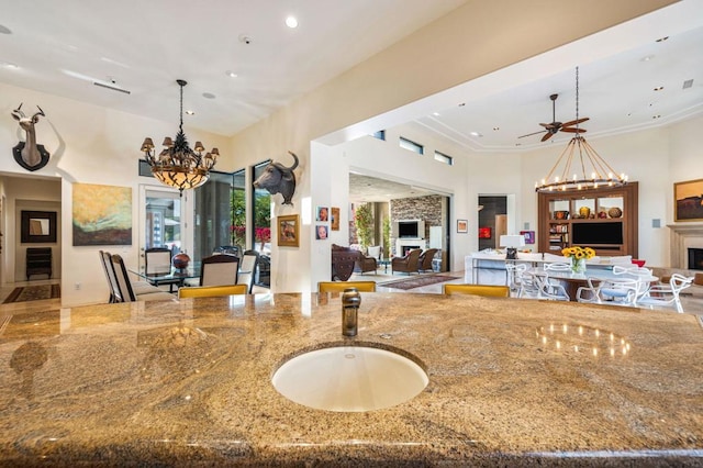 kitchen with crown molding, sink, stone countertops, and ceiling fan with notable chandelier