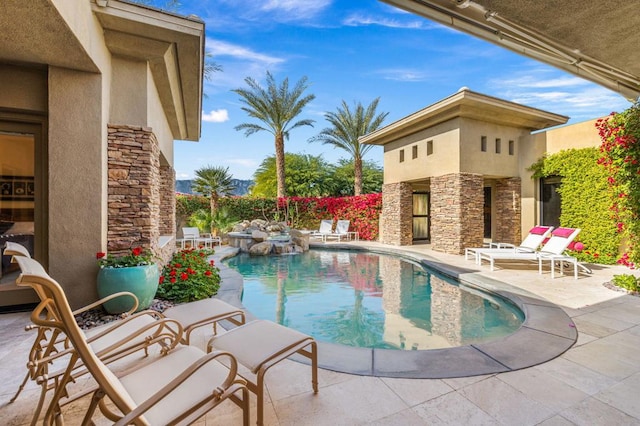 view of swimming pool featuring a patio area and exterior fireplace