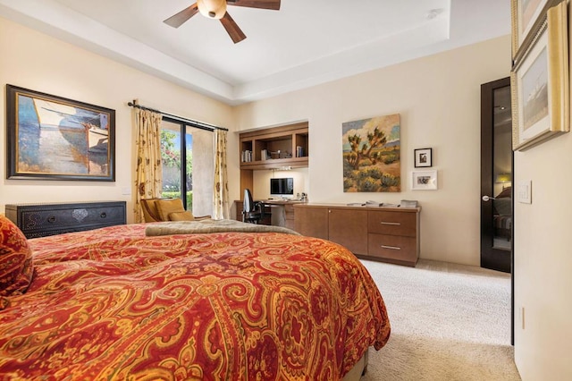 bedroom with ceiling fan, light colored carpet, and a tray ceiling