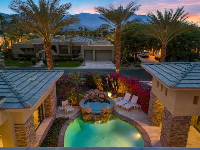 pool at dusk featuring a mountain view and a patio