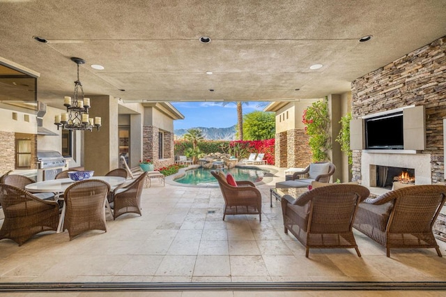 view of patio with an outdoor stone fireplace, area for grilling, and a pool with hot tub