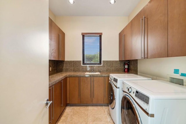 laundry area featuring cabinets, sink, light tile patterned flooring, and washing machine and clothes dryer