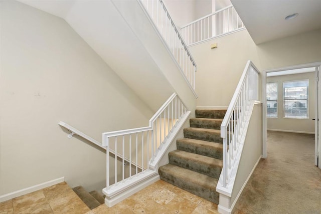 stairs with carpet and a towering ceiling