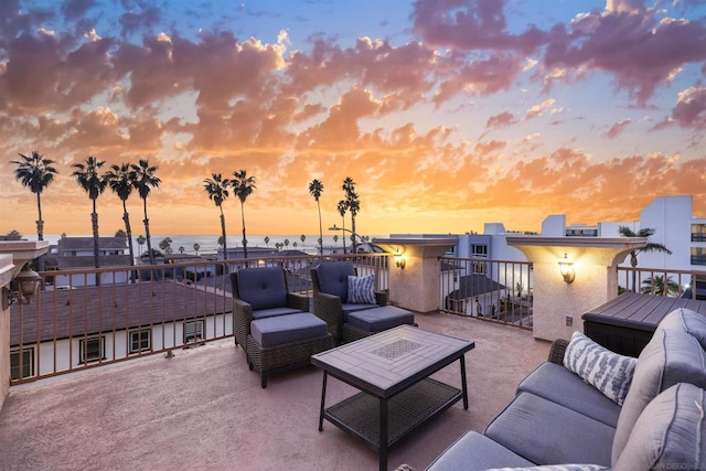 patio terrace at dusk featuring outdoor lounge area and a balcony