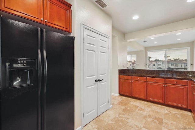 kitchen featuring black fridge with ice dispenser and dark stone countertops