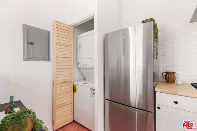 laundry area featuring stacked washer / drying machine and electric panel