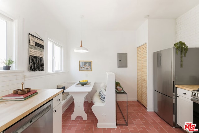 kitchen with breakfast area, appliances with stainless steel finishes, electric panel, pendant lighting, and white cabinets