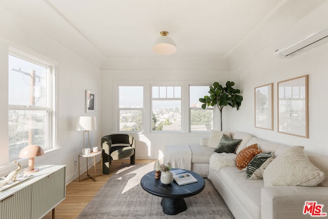 living room with a wall mounted air conditioner and light wood-type flooring