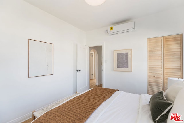 bedroom with a wall mounted air conditioner and a closet