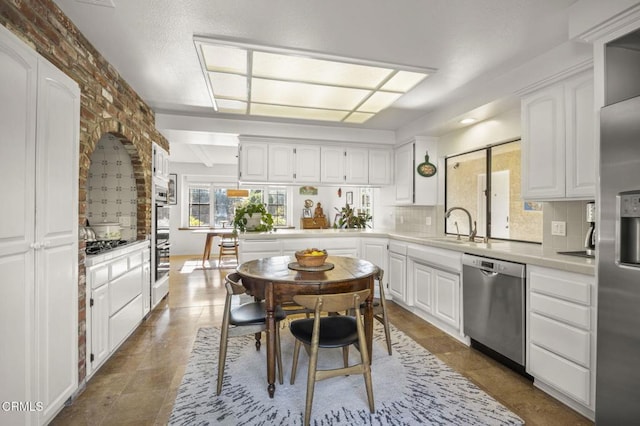 kitchen featuring white cabinets, stainless steel appliances, tasteful backsplash, and sink