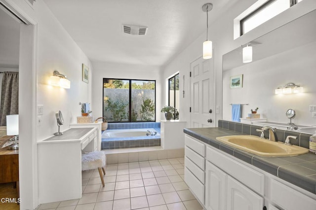 bathroom featuring tile patterned floors, vanity, and tiled bath