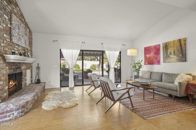 living room featuring hardwood / wood-style floors, lofted ceiling, and a brick fireplace