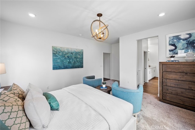 carpeted bedroom featuring ensuite bath and an inviting chandelier