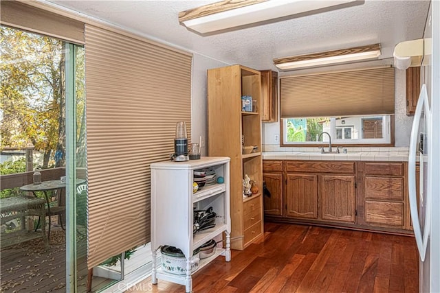 kitchen featuring tile counters, sink, dark hardwood / wood-style flooring, white refrigerator, and a textured ceiling