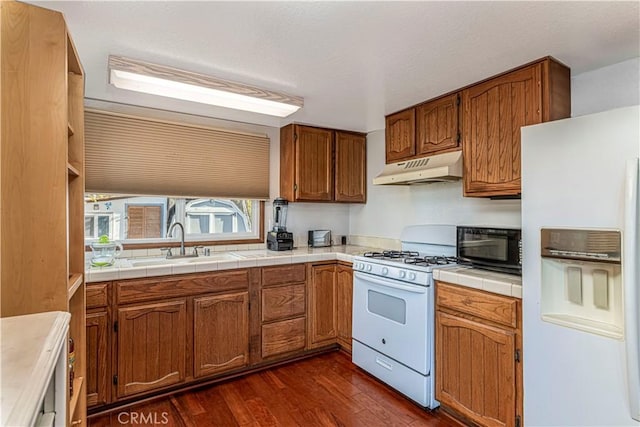 kitchen with dark hardwood / wood-style flooring, white appliances, tile counters, and sink