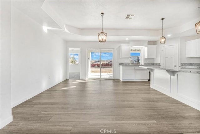 kitchen featuring white cabinetry, a kitchen bar, decorative light fixtures, and hardwood / wood-style floors