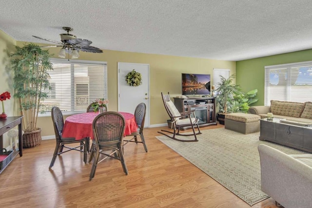 dining area with ceiling fan, a healthy amount of sunlight, light wood-type flooring, and a textured ceiling