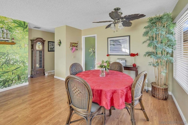 dining space with ceiling fan, a textured ceiling, and light wood-type flooring